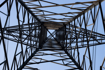 High voltage electricity transmission tower bottom view under the blue sky in the evening