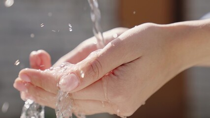 a stream of wet transparent clean water is poured onto the hands, observe the hygiene of clean human skin, moisturize and wash fingers, clean and wash after work, wash off the dirt, close-up