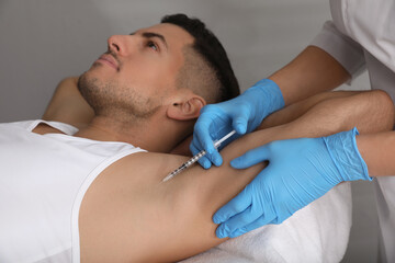 Cosmetologist injecting man's armpit in clinic. Treatment of hyperhidrosis - obrazy, fototapety, plakaty