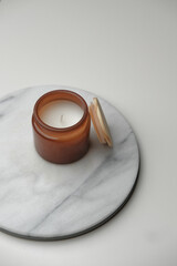 Brown glass candle jar from above. Minimal geometric white and marble background. Product still life photography concept