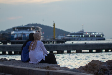 Girls in burqa sit on the shores of Buyukada island, Turkey, Istanbul, Adalar Islands