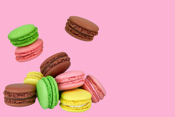 French macaroons flying in the air isolated on a pink background.