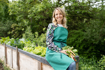 woman harvests chard in her own garden and is happy