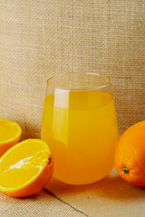 Fresh glass of juice with oranges around. Vertical shot.
