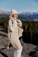 woman in autumn clothes stands on a rock blue sky relaxation