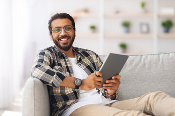 Handsome indian man chilling at home with digital tablet