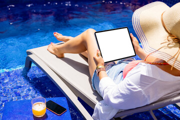 Woman using tablet computer by the pool