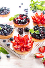 Fresh berries and ricotta cheese in tartletes. Summer dessert, healthy breakfast or snack, open sandwiches with strawberry, blueberries, blackberries.