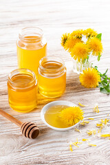 Dandelion honey in a jar and fresh flowers on a table