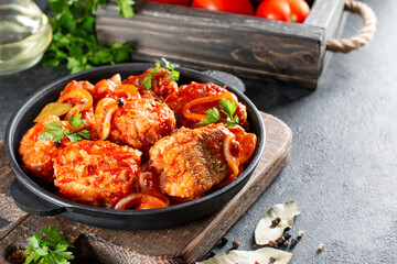 Traditional Brazilian fish stew moqueca baiana with fish filet in tomato sauce as closeup in a cast-iron roasting dish