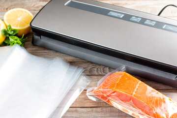 Vacuum packing machine and fish in a plastic bag on wooden background. Sous-vide