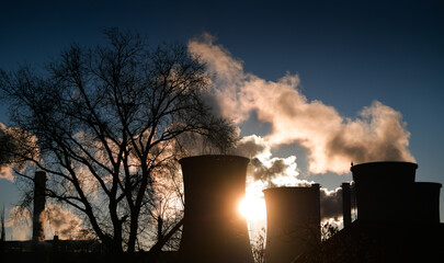 Central heating system. Smoke is getting out of cooling chimney of a thermal power plant. Pollution inside a city, danger for the environment.