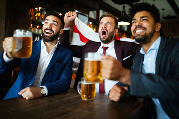Men fans screaming and watching football on TV and drink beer in a pub