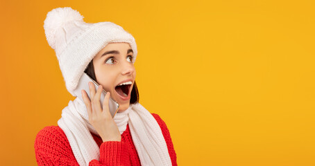 Wow offer. Surprised lady in winter outfit talking on smartphone and looking at free space on...