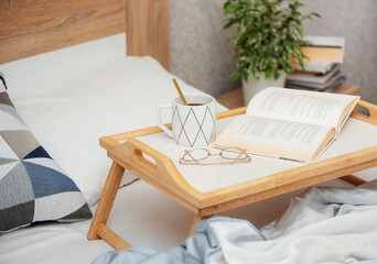 Cup of coffee and book on bed