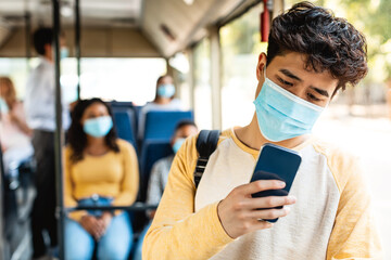 Asian guy in mask using phone in bus