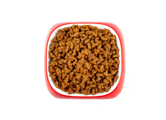 Dry food for cats and dogs in a red bowl on a white background, top view