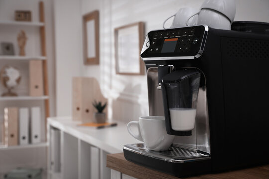 Modern coffee machine with cup in office. Space for text