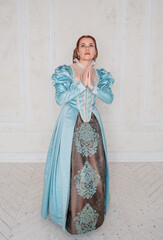 Beautiful young woman in medieval style blue dress praying