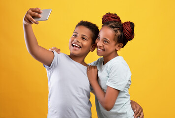 Loving afro-american siblings taking selfie together on cellphone