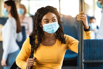 Portrait of black woman in face mask standing in bus