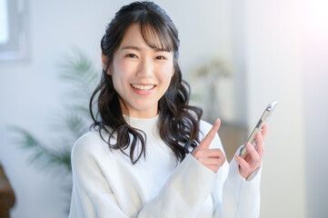 笑顔でスマホでタップする美しい日本人女性　アップ　カメラ目線