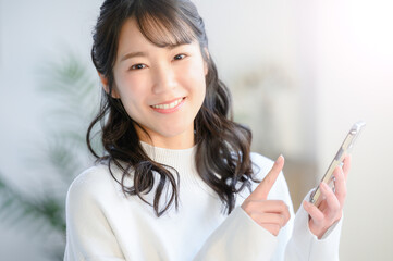 笑顔でスマホをタップする美しい日本人女性　アップ　カメラ目線