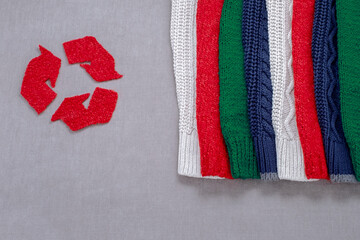 Recycle symbol made from old woolen clothes on grey background, top view, flat lay. Responsible...