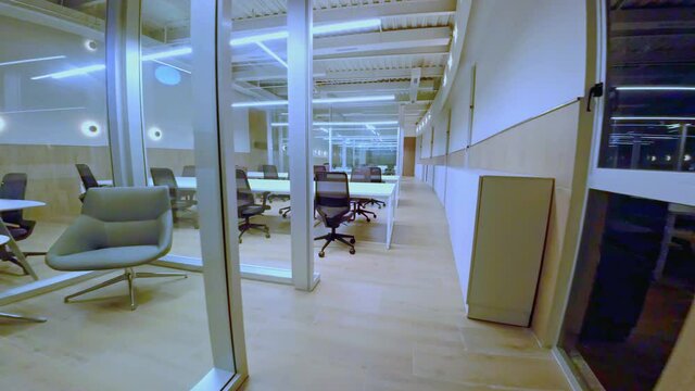 Drone flying between desks and empty tables of deserted office. Aerial view