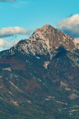 Fototapeta premium Alpine peak in the autumn on blue sky with clouds