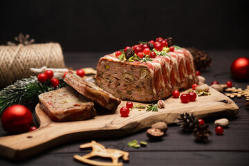 Traditional French terrine covered with bacon on dark wooden background with Christmas decorations