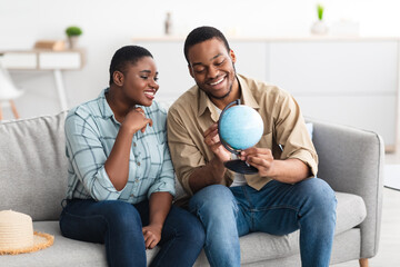 Black Couple Holding Globe Choosing Country For Next Vacation Indoors