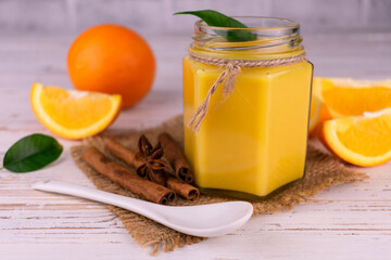 Homemade orange curd in a jar on a light background.