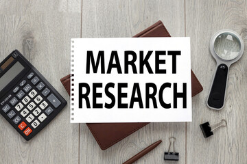 Market research text on sheet of paper on wood table with stationery and brown notepad for business...