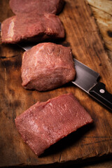 Raw game meat, beef. Pieces of red meat on wooden cutting board. High quality roe, deer, fallow deer meat.