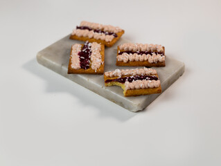 Traditional australian dessert iced vovo. Biscuit cookies with fudge and raspberries jam, sprinkled coconut flake . Keto dessert made from almond flour, sweetener instead of sugar.