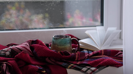 Steaming coffee cup on a rainy day window background. cozy atmosphere, in cold weather. Rainy Day Mood. warming home atmosphere