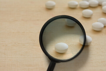 Magnifying glass and white pills