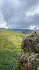 A girl sitting on top of a rock against the backdrop of mountain landscapes in the Elbrus region, Kabardino-Balkaria