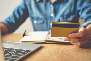 Hands holding credit card with using laptop.