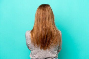Naklejka premium Young redhead woman isolated on blue background in back position