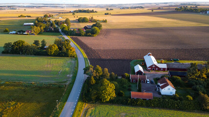 Aerial view of old red wooden farms with road during sunset in Sweden © Clara
