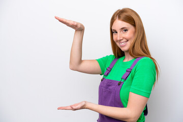 Young redhead woman isolated on white background holding copyspace to insert an ad