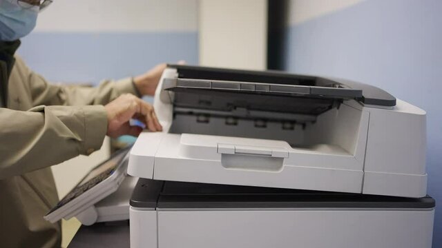 Hand of man is using a photocopier to copy documents.