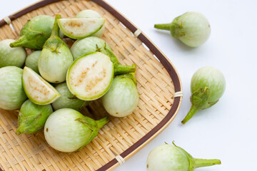 Organic green eggplant in bamboo basket on white background