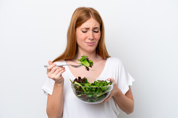 Young redhead woman isolated on white background holding a bowl of salad with sad expression