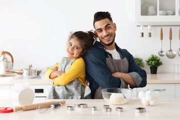 Fototapeta premium Family Baking. Happy Arab Dad And Daughter In Aprons Posing In Kitchen