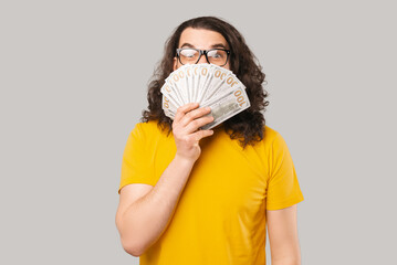 Photo of young excited young man holding money over face.
