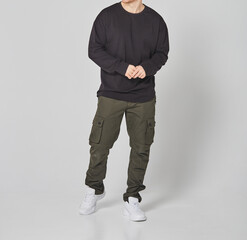 Cropped shot of man in black blank long sleeved and green cargo pants. Standing on gray background. Mockup for print or design template. Basic clothing line no logo