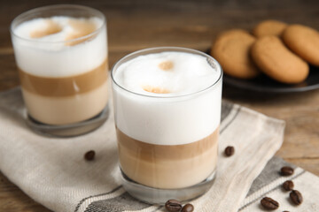 Delicious latte macchiato and coffee beans on wooden table